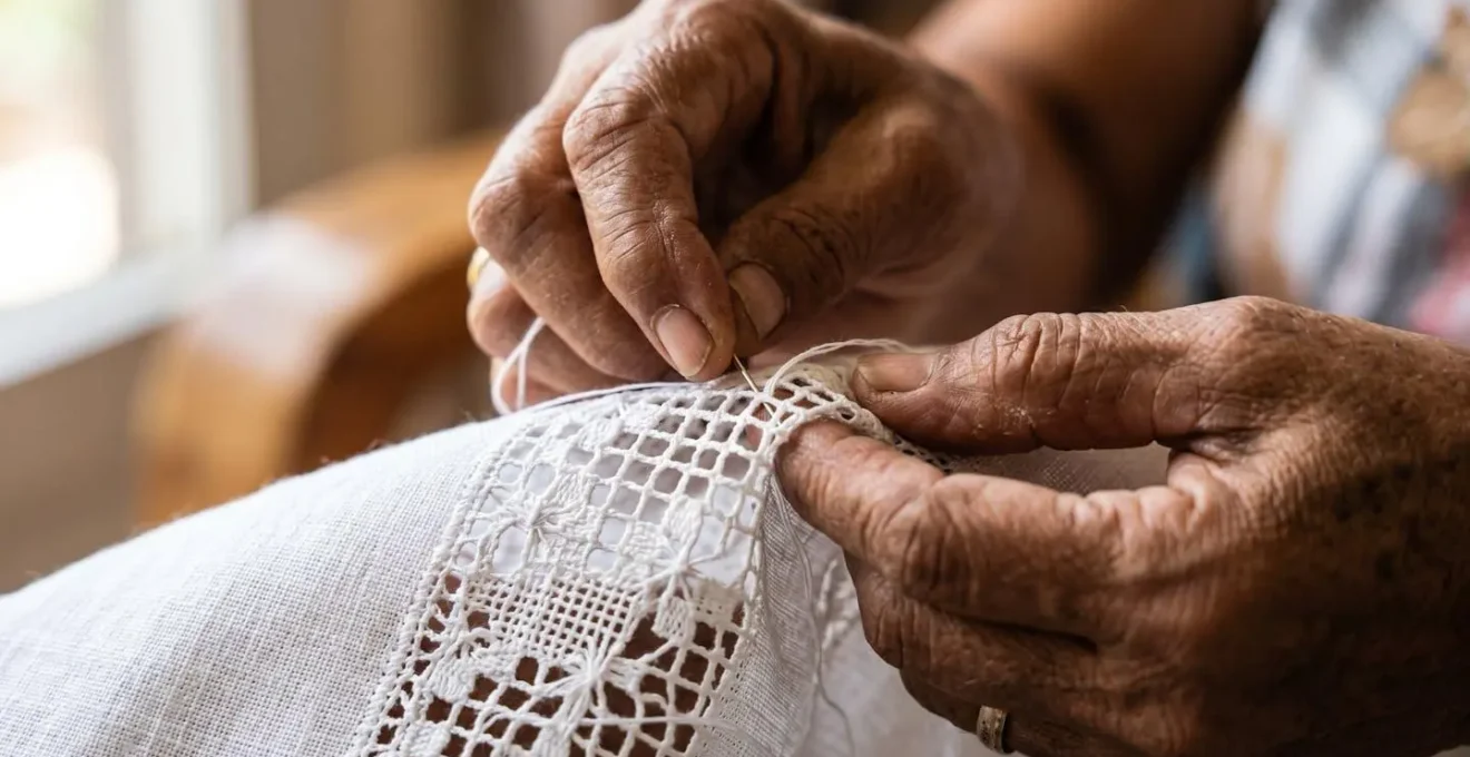 Mains d'une brodeuse travaillant sur un napperon traditionnel de Cilaos