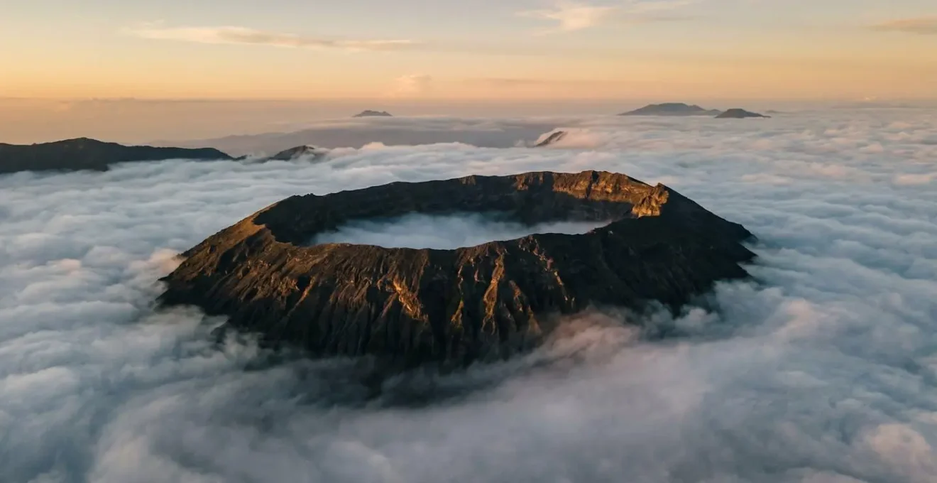 Vue aérienne du cratère Dolomieu émergeant du brouillard comme un repère de navigation
